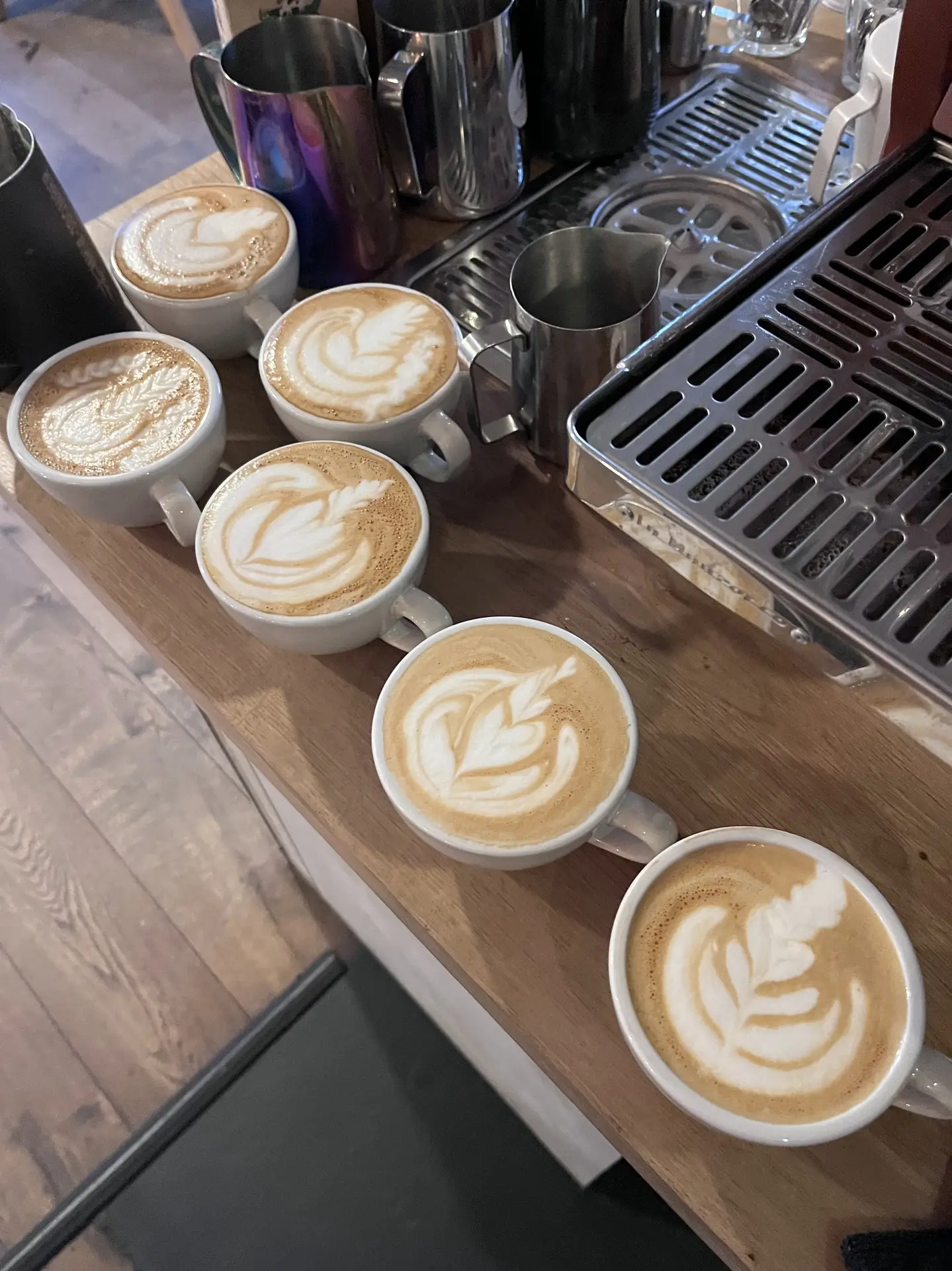Vier kopjes met latte art naast elkaar