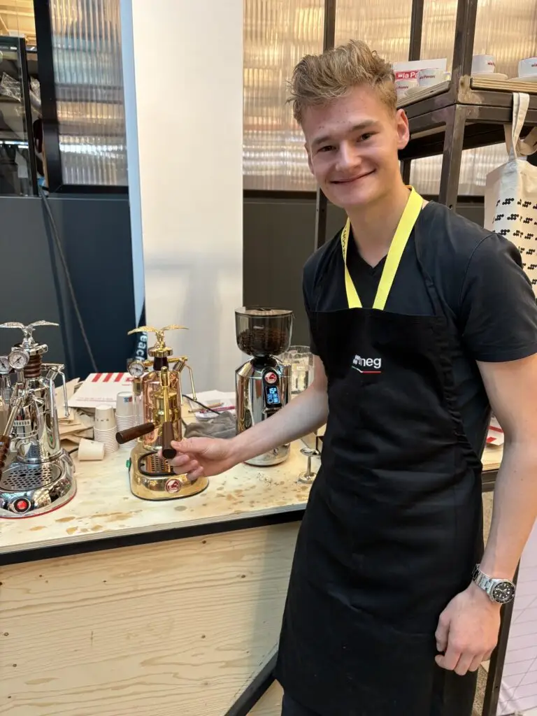 Jordy in schort naast twee espressomachines