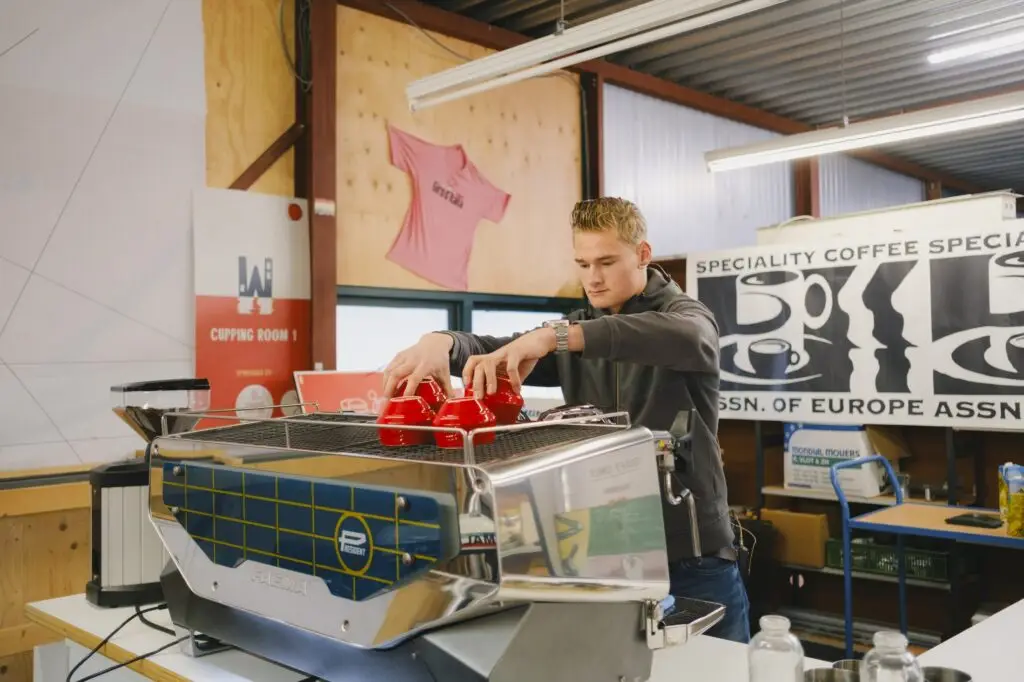 Jordy zet kopjes klaar op de espressomachine