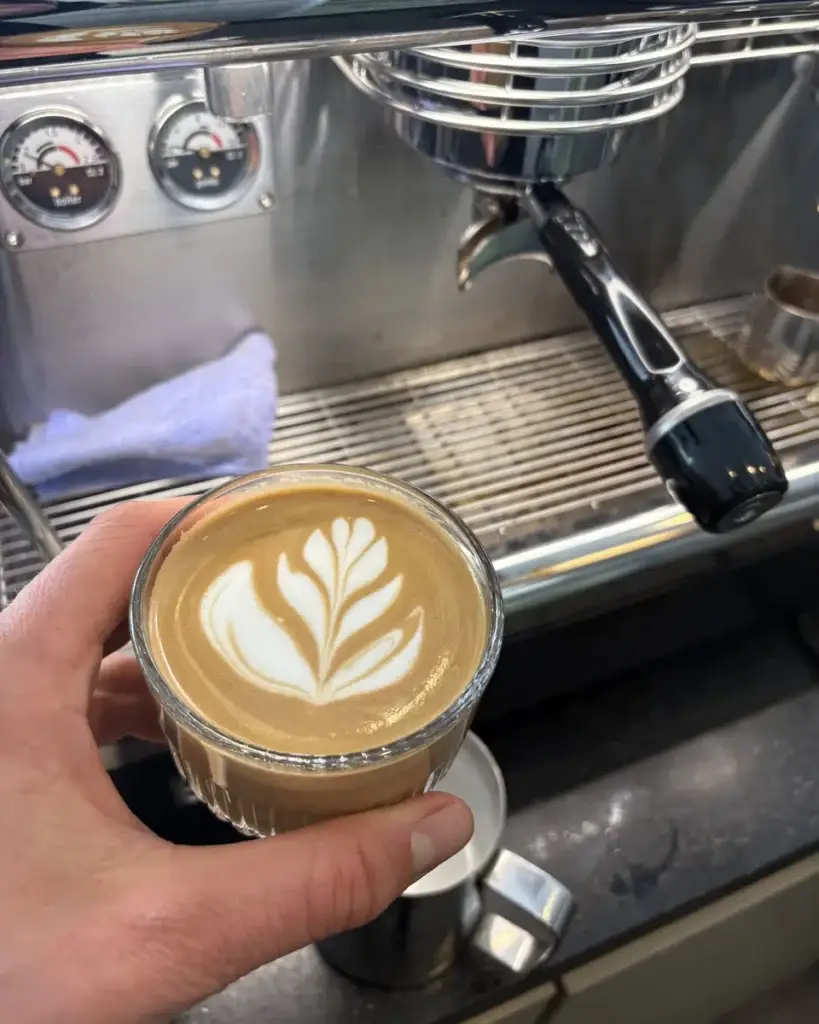 Latte art in een glas bij de espressomachine