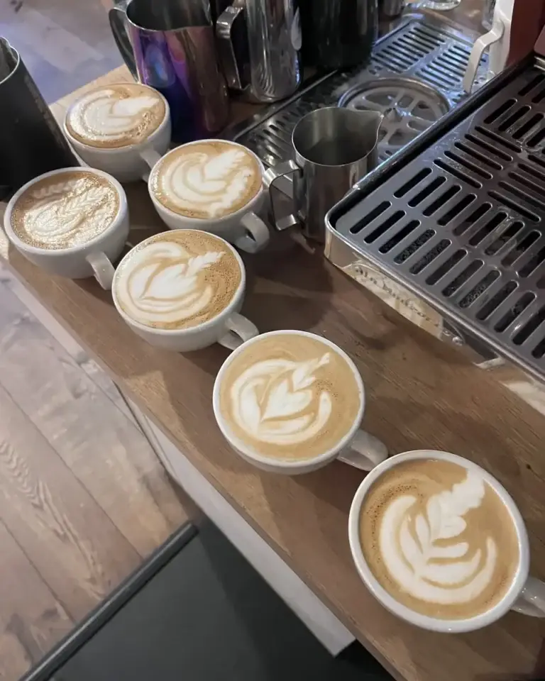 Vier kopjes met latte art naast elkaar