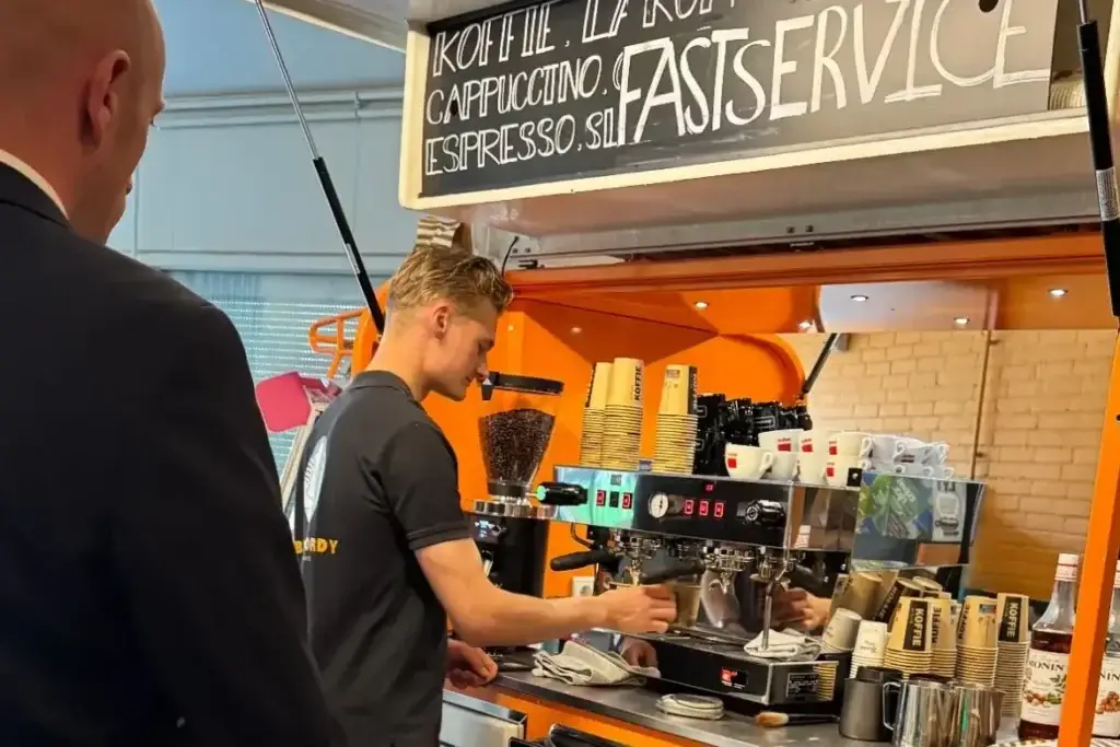 Jordy zet koffie achter de koffie-Piaggio van het Nova College