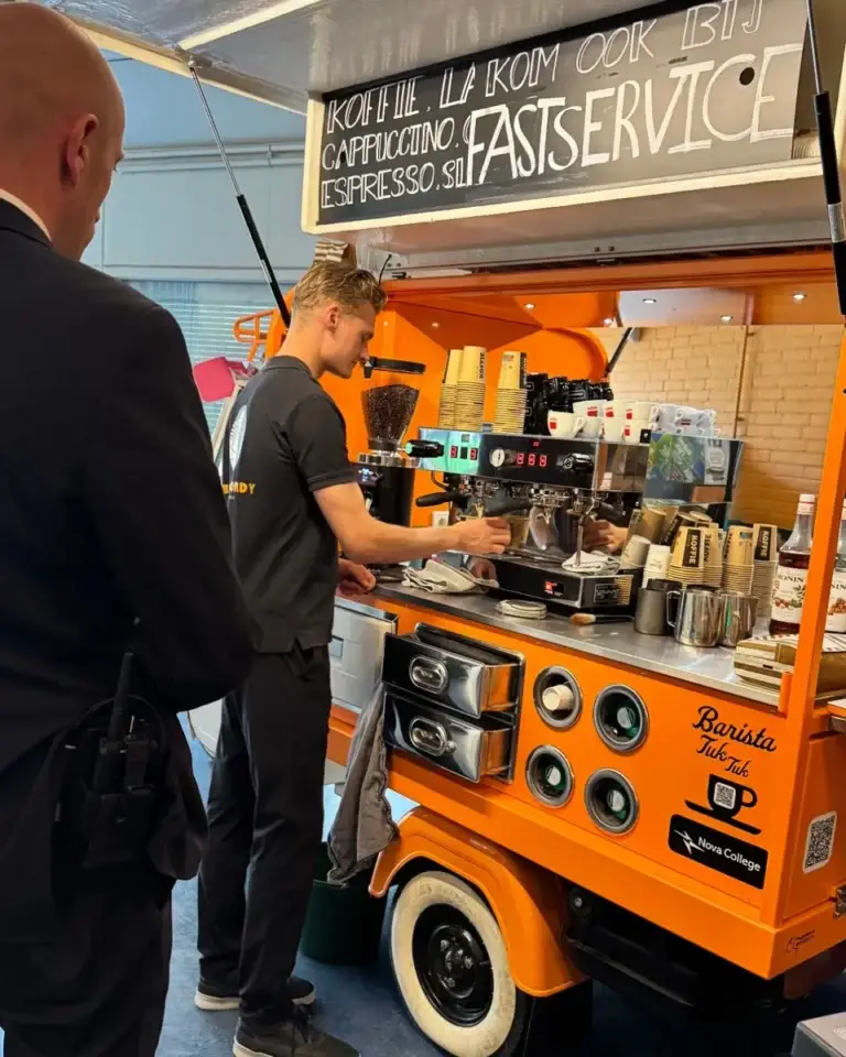 Jordy zet koffie achter de koffie-Piaggio van het Nova College